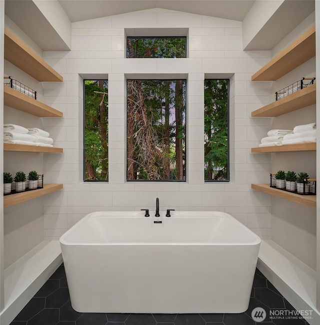 1704 172nd Ct NE, Bellevue, WA 98008 - bathroom featuring a soaking tub, tile patterned flooring, vaulted ceiling, and tile walls