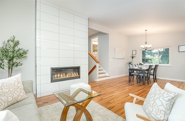 14249 NE 1st St, Bellevue, WA 98007 - living room featuring a chandelier, a tiled fireplace, light wood-style flooring, and stairs