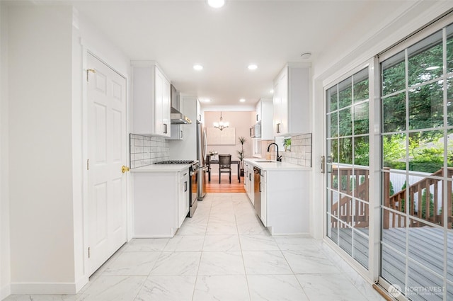 14249 NE 1st St, Bellevue, WA 98007 - kitchen with stainless steel appliances, light countertops, wall chimney exhaust hood, tasteful backsplash, and a chandelier