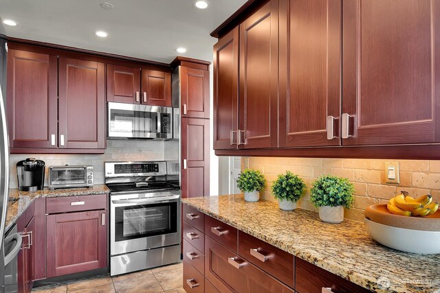 500 W Olympic Pl Unit 401, Seattle, WA 98119 - kitchen featuring appliances with stainless steel finishes, recessed lighting, tasteful backsplash, light stone countertops, and reddish brown cabinets