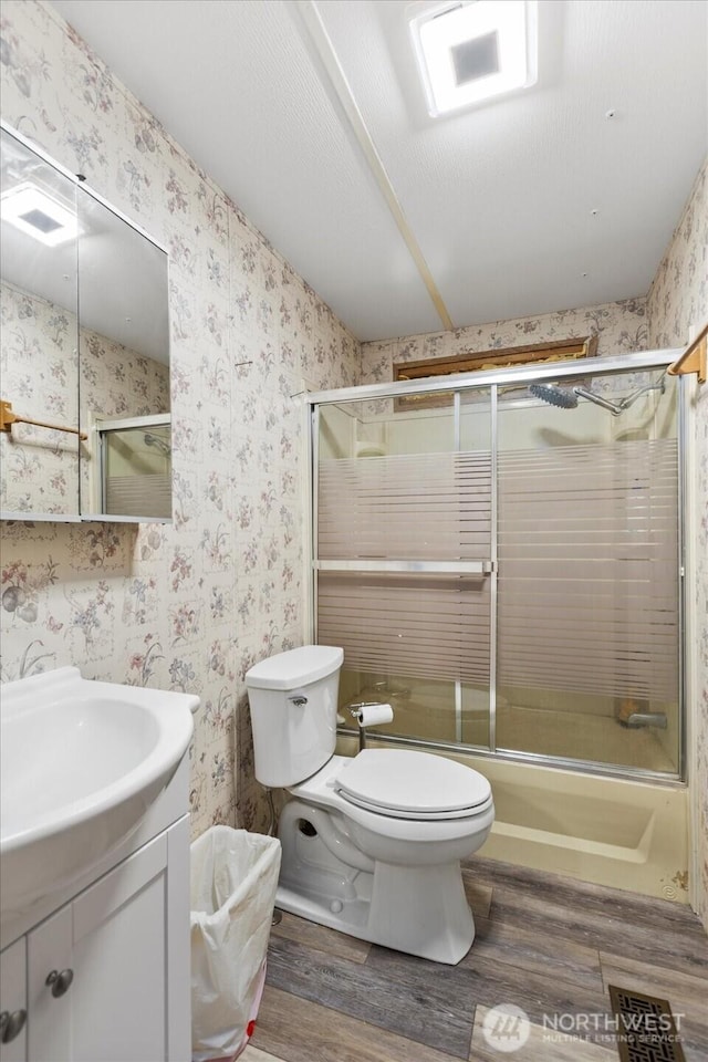 18025 Cedar Ponds Rd, Monroe, WA 98272 - full bath with wood finished floors, wallpapered walls, vanity, and bath / shower combo with glass door