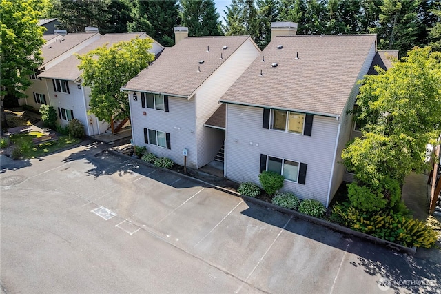 4231 NE 5th St Unit C102, Renton, WA 98059 - view of front of property with a chimney, roof with shingles, and view of wooded area