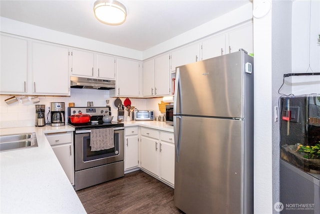 4231 NE 5th St Unit C102, Renton, WA 98059 - kitchen featuring stainless steel appliances, under cabinet range hood, light countertops, dark wood-style floors, and backsplash