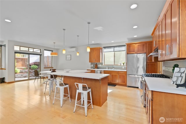 3800 SW Holden St, Seattle, WA 98126 - kitchen featuring appliances with stainless steel finishes, a breakfast bar, brown cabinetry, decorative backsplash, and recessed lighting