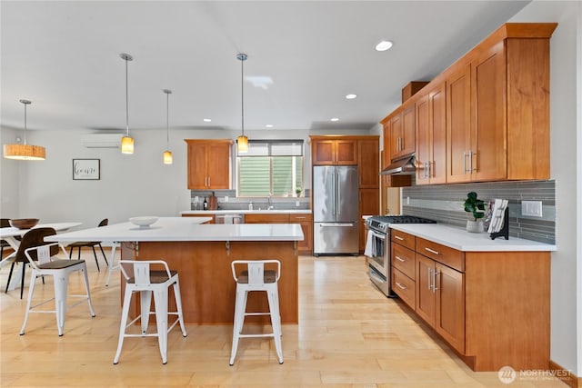 3800 SW Holden St, Seattle, WA 98126 - kitchen featuring appliances with stainless steel finishes, a wall unit AC, a kitchen bar, light countertops, and decorative backsplash