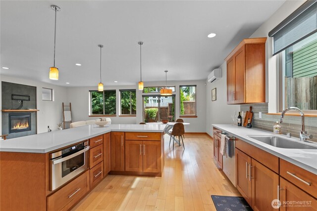 3800 SW Holden St, Seattle, WA 98126 - kitchen featuring appliances with stainless steel finishes, an AC wall unit, light countertops, tasteful backsplash, and light wood-style floors