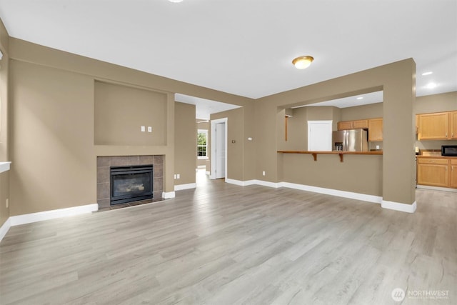 18527 97th Ave E, Puyallup, WA 98375 - unfurnished living room featuring light wood-type flooring, a tiled fireplace, and recessed lighting