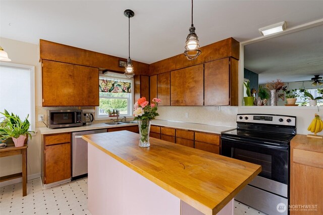 1328 Grant St, Walla Walla, WA 99362 - kitchen with appliances with stainless steel finishes, wooden counters, backsplash, hanging light fixtures, and brown cabinetry