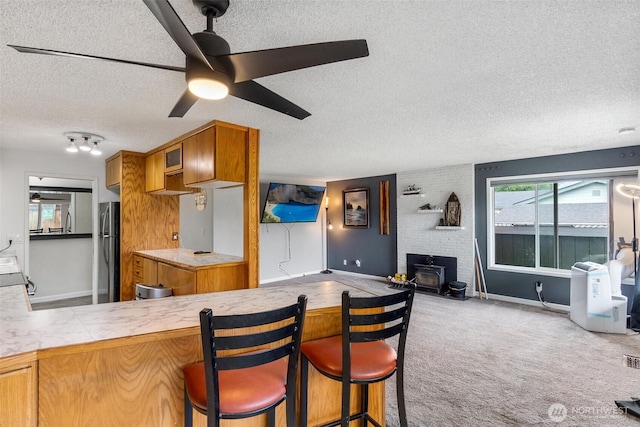 1401 Lum Rd, Centralia, WA 98531 - kitchen featuring a textured ceiling, freestanding refrigerator, a wood stove, brown cabinetry, and ceiling fan