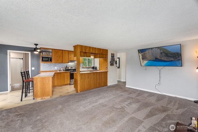 1401 Lum Rd, Centralia, WA 98531 - kitchen featuring stainless steel range with electric stovetop, black microwave, brown cabinets, a peninsula, and a textured ceiling