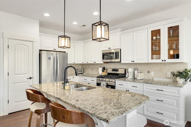 1803 65th Ct SE, Tumwater, WA 98501 - kitchen featuring appliances with stainless steel finishes, white cabinets, dark wood-style flooring, a kitchen bar, and light stone counters
