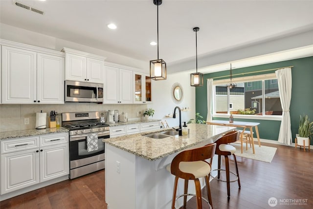 1803 65th Ct SE, Tumwater, WA 98501 - kitchen with appliances with stainless steel finishes, white cabinets, dark wood-style flooring, hanging light fixtures, and light stone counters