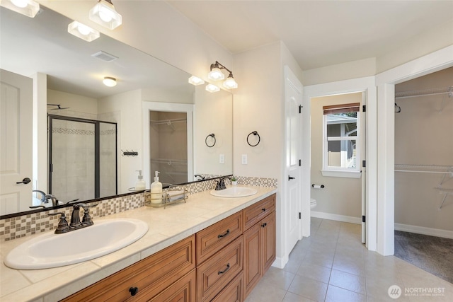 1803 65th Ct SE, Tumwater, WA 98501 - full bathroom with a walk in closet, double vanity, a shower stall, and tile patterned flooring