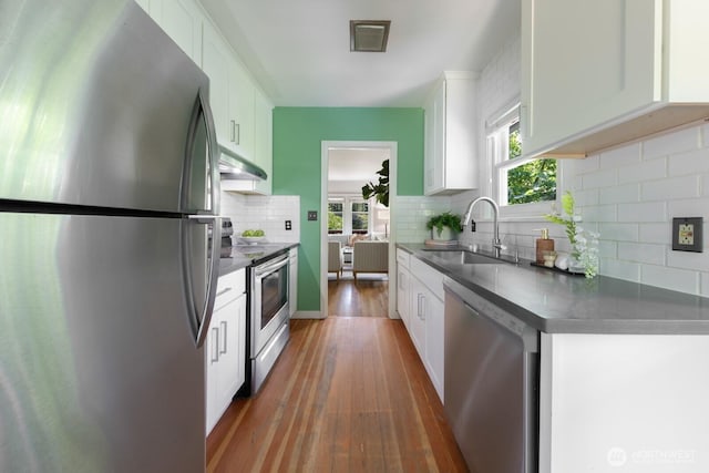 2110 N 88th St, Seattle, WA 98103 - kitchen featuring stainless steel appliances, wood-type flooring, decorative backsplash, white cabinets, and under cabinet range hood