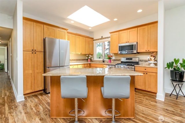 502 SW 326th St, Federal Way, WA 98023 - kitchen with stainless steel appliances, a skylight, a center island, light wood finished floors, and recessed lighting