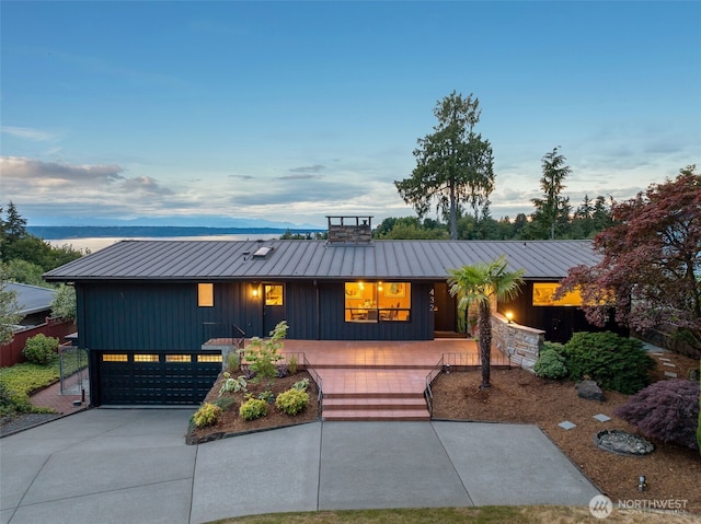 432 SW 206th St, Normandy Park, WA 98166 - view of front of property featuring a metal roof, concrete driveway, a standing seam roof, a chimney, and board and batten siding