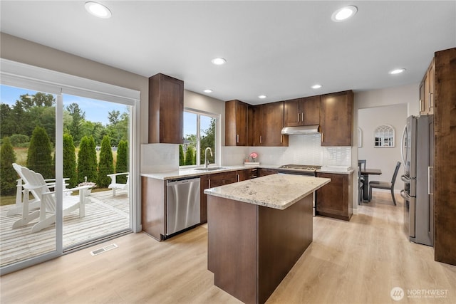 21206 9th Ave SE, Bothell, WA 98021 - kitchen with stainless steel appliances, light wood-style floors, a center island, under cabinet range hood, and tasteful backsplash