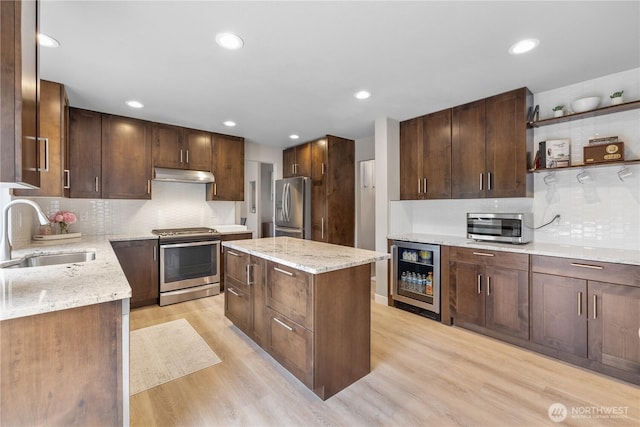 21206 9th Ave SE, Bothell, WA 98021 - kitchen featuring appliances with stainless steel finishes, beverage cooler, under cabinet range hood, light wood-type flooring, and a center island