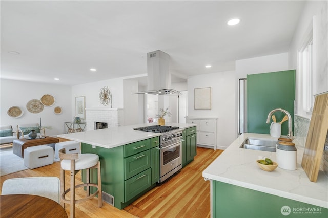 13247 2nd Ave NW, Seattle, WA 98177 - kitchen featuring green cabinets, high end stainless steel range, island exhaust hood, light wood finished floors, and a brick fireplace