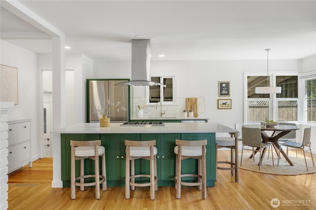 13247 2nd Ave NW, Seattle, WA 98177 - kitchen featuring island exhaust hood, stainless steel appliances, light wood-style flooring, tasteful backsplash, and a spacious island