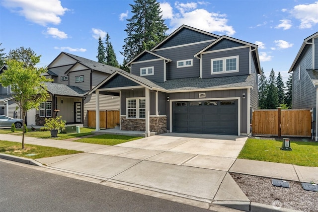 8665 Kimmie Loop SW, Tumwater, WA 98512 - craftsman-style house with board and batten siding, concrete driveway, an attached garage, a shingled roof, and stone siding