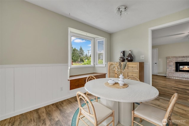 120 E Mason Ave, Buckley, WA 98321 - dining space with wood finished floors, a brick fireplace, and a wainscoted wall