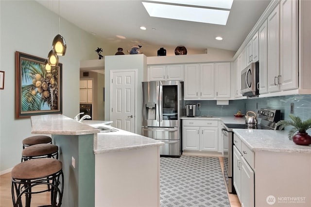 2237 Mcdonald Ave, Dupont, WA 98327 - kitchen featuring stainless steel appliances, a skylight, white cabinetry, backsplash, and lofted ceiling