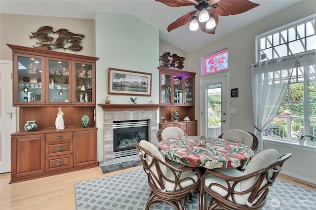 2237 Mcdonald Ave, Dupont, WA 98327 - dining space featuring a ceiling fan, light wood-type flooring, a tiled fireplace, and vaulted ceiling