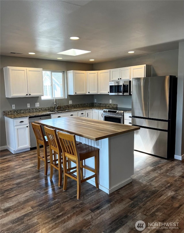 1042 S Lakeland Dr, Moses Lake, WA 98837 - kitchen featuring appliances with stainless steel finishes, butcher block counters, a skylight, white cabinetry, and dark wood-style flooring