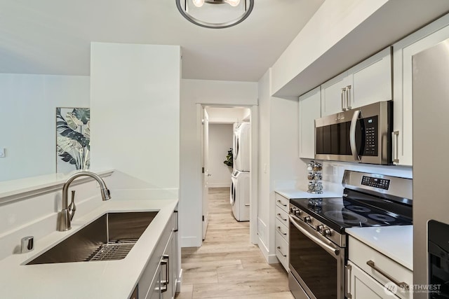 5589 Lakemont Blvd SE Unit 1703, Bellevue, WA 98006 - kitchen featuring appliances with stainless steel finishes, stacked washer and clothes dryer, light wood-style floors, and light countertops