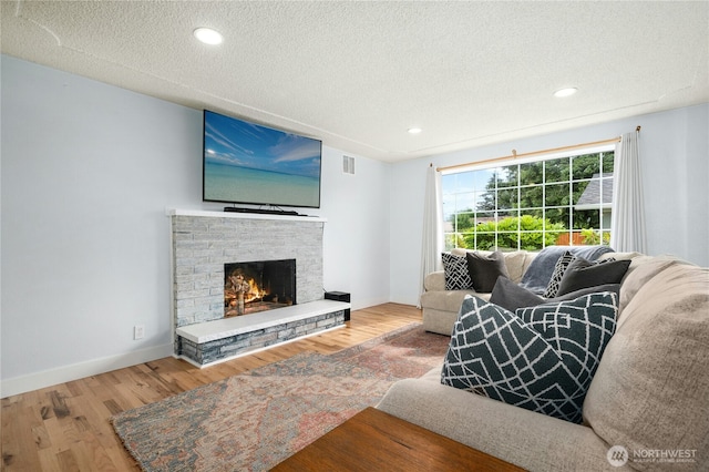 1037 Harding St, Enumclaw, WA 98022 - living room with wood finished floors, a textured ceiling, a fireplace, and recessed lighting