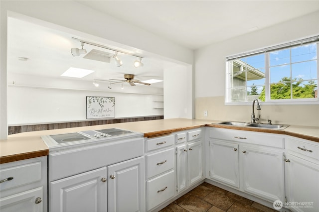 1037 Harding St, Enumclaw, WA 98022 - kitchen featuring a skylight, white cabinetry, light countertops, ceiling fan, and stovetop