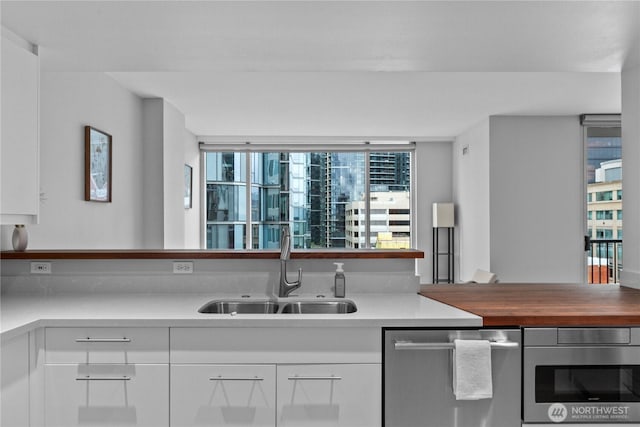 177 NE 107th Ave Unit 1601, Bellevue, WA 98004 - kitchen featuring dishwasher, white cabinetry, wall oven, and wooden counters