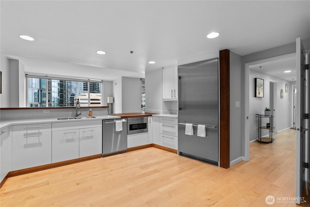 177 NE 107th Ave Unit 1601, Bellevue, WA 98004 - kitchen featuring appliances with stainless steel finishes, white cabinetry, recessed lighting, light wood-style flooring, and light countertops