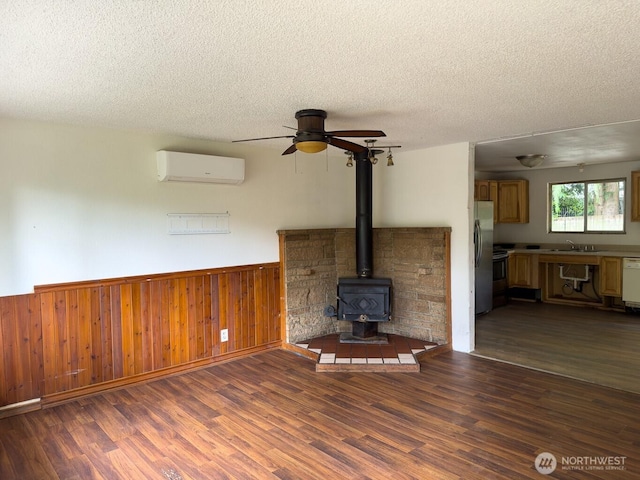 6420 NE Nelson St, Suquamish, WA 98392 - unfurnished living room with a wall mounted AC, a textured ceiling, wainscoting, wood finished floors, and a ceiling fan