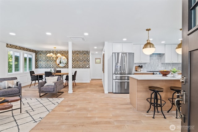 7006 20th Ave NE, Seattle, WA 98115 - kitchen with stainless steel fridge, a chandelier, light countertops, decorative light fixtures, and white cabinetry