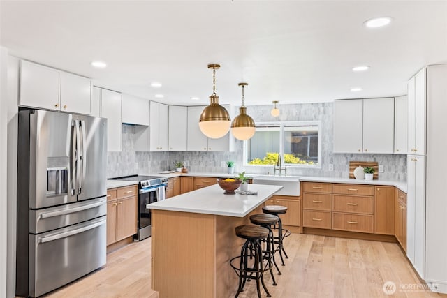 7006 20th Ave NE, Seattle, WA 98115 - kitchen with stainless steel appliances, light wood-style flooring, a kitchen bar, decorative backsplash, and recessed lighting