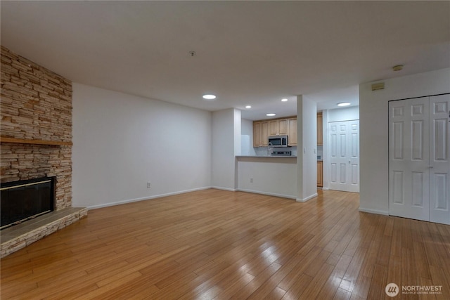 2969 142nd Pl SE # 8, Bellevue, WA 98007 - unfurnished living room with a stone fireplace, recessed lighting, and light wood-style floors