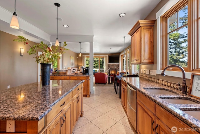 6730 Forest Ridge Dr, Wenatchee, WA 98801 - kitchen featuring brown cabinets, light tile patterned floors, hanging light fixtures, dark stone countertops, and a center island