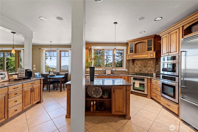 6730 Forest Ridge Dr, Wenatchee, WA 98801 - kitchen featuring open shelves, stainless steel appliances, dark stone countertops, brown cabinetry, and light tile patterned floors