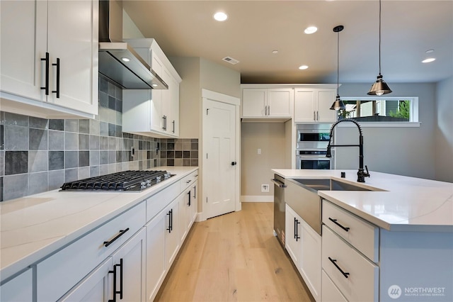 26517 NE 147th Pl Unit Sr 13, Duvall, WA 98019 - kitchen with wall chimney exhaust hood, appliances with stainless steel finishes, light wood-style flooring, pendant lighting, and white cabinets