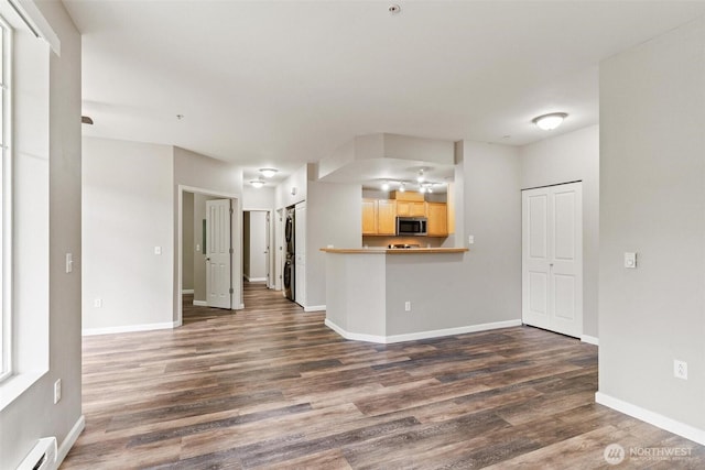 15325 SE 155th Pl Unit N-2, Renton, WA 98058 - unfurnished living room featuring a baseboard radiator, dark wood-type flooring, and stacked washer and clothes dryer