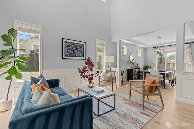 8122 NE 189th Pl, Kenmore, WA 98028 - living room featuring a chandelier, light wood finished floors, a decorative wall, wainscoting, and a raised ceiling