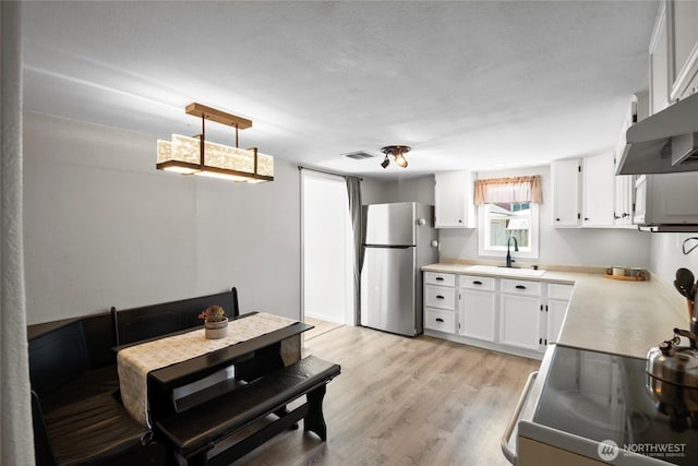 1580 134th Ln, Long Beach, WA 98631 - kitchen with freestanding refrigerator, range with electric cooktop, white cabinetry, light countertops, and wall chimney range hood