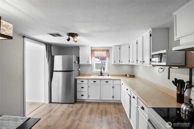 1580 134th Ln, Long Beach, WA 98631 - kitchen featuring appliances with stainless steel finishes, white cabinets, light wood-style flooring, and light countertops