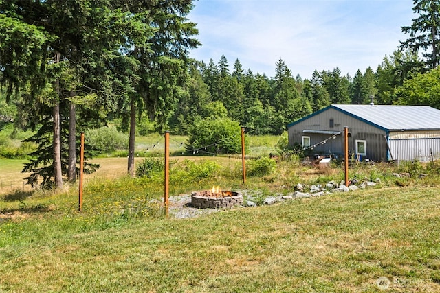 32205 71st Ave S, Roy, WA 98580 - view of grassy yard with an outdoor fire pit, a pole building, an outbuilding, a garage, and a view of trees
