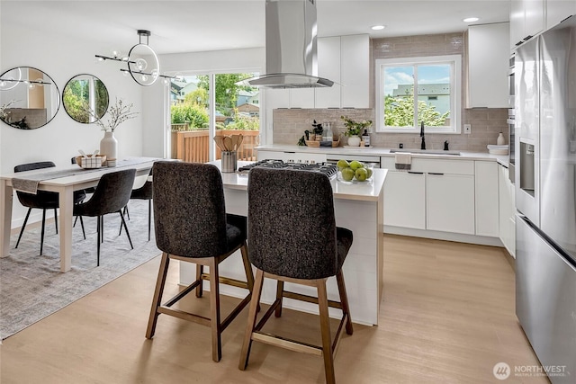320 178th Pl SW, Bothell, WA 98012 - kitchen featuring appliances with stainless steel finishes, island exhaust hood, light wood finished floors, a kitchen bar, and light countertops