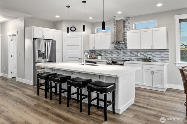 101 Wren Loop SW, Mattawa, WA 99349 - kitchen featuring stainless steel appliances, wall chimney range hood, a kitchen bar, backsplash, and light countertops