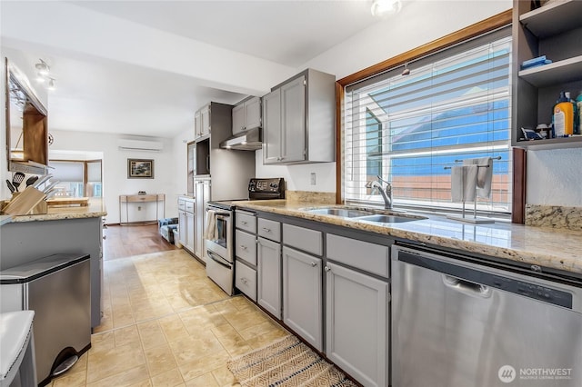 10208 D St E, Tacoma, WA 98445 - kitchen featuring appliances with stainless steel finishes, under cabinet range hood, gray cabinetry, an AC wall unit, and light stone countertops