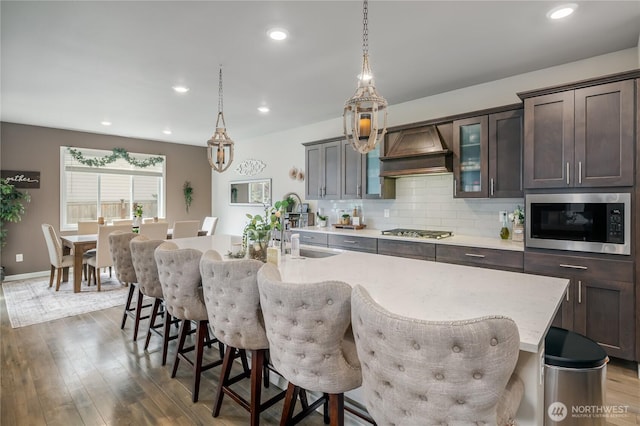 1448 101st Ave SE, Lake Stevens, WA 98258 - kitchen featuring built in microwave, custom exhaust hood, stainless steel gas cooktop, a kitchen bar, and a center island with sink